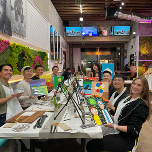 Group of people in a studio or art class holding up their artwork.