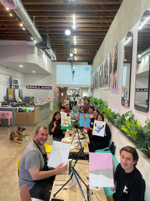 Group of people in a modern office setting with artwork and plants.